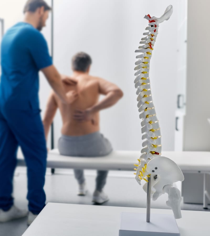 A physician is diagnosing a back pain area of the patient for balloon kyphoplasty surgery.
