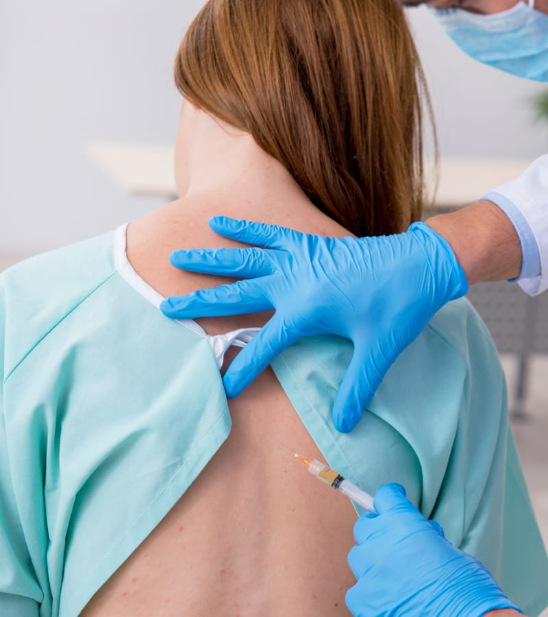 A woman is given a spinal injection for back and neck pain relief.