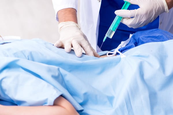 Patient is receiving a spine injection from the doctor.