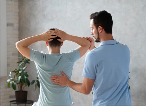 A therapist helps a patient with post spine surgery rehabilitation.