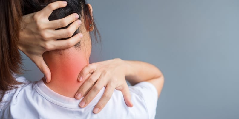 Woman holding neck in pain illustrates the red flags that must not be ignored.