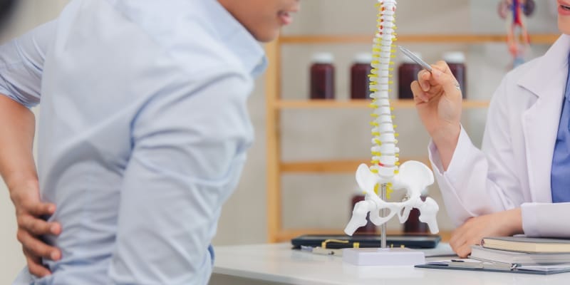 A spine doctor explaining treatment options to a patient during a medical consultation about possible spine surgery.